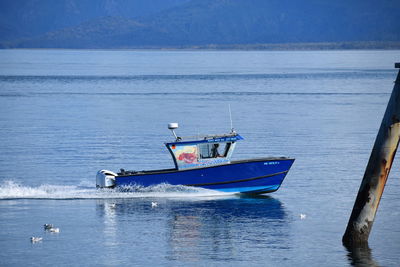 Boat moored in sea against blue sky
