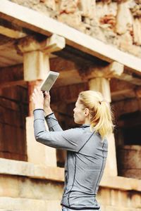 Woman photographing through digital tablet at old ruins