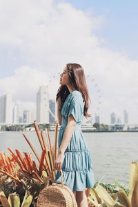 Woman with arms outstretched against sky in city