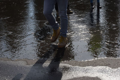 Low section of man standing on wet road during rainy season