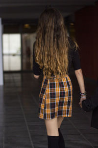 Rear view of woman with brown hair walking in corridor