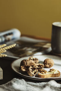 Bread toast with butter and walnuts on a plate in a cozy wooden table