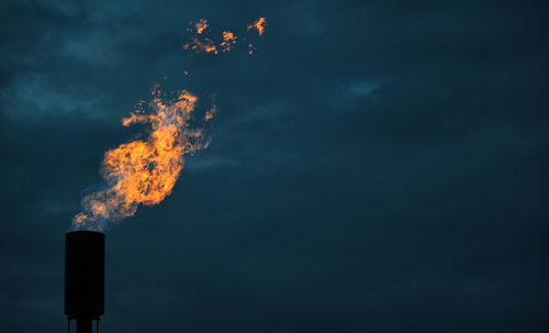 Methane gas flare burns in a twilight sky