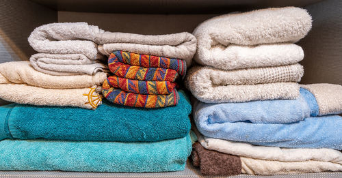 Pile of various types of towels and beach towels colored in different shades inside a wardrobe