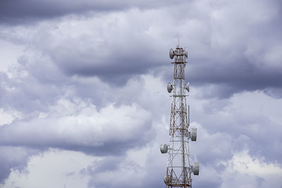 Low angle view of communications tower against cloudy sky