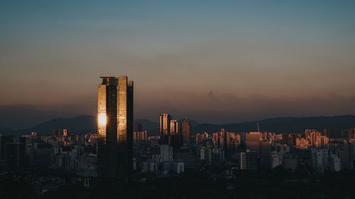 Modern buildings against sky during sunset