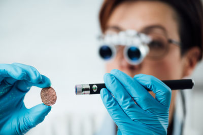 Numismatics expert examines a collection of coins, using magnifying goggles