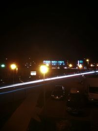 Illuminated street against sky at night