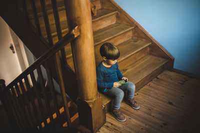 High angle view of boy sitting on staircase at home