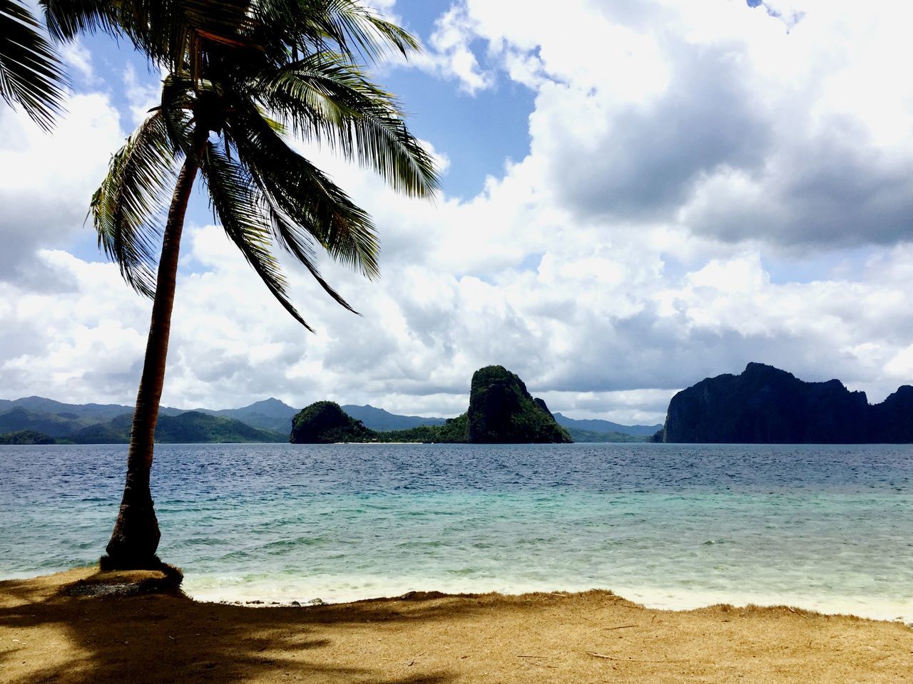 sky, water, tranquil scene, tranquility, sea, scenics, beauty in nature, cloud - sky, tree, beach, nature, palm tree, cloud, shore, mountain, cloudy, idyllic, rock - object, non-urban scene, growth