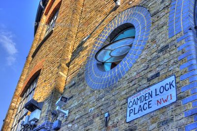 Low angle view of text on building against blue sky