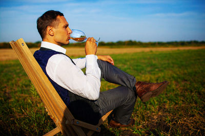 Man drinks wine on meadow
