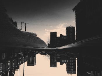 Upside down image of buildings reflection in puddle on road
