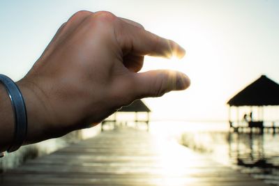 Midsection of person against sea during sunset