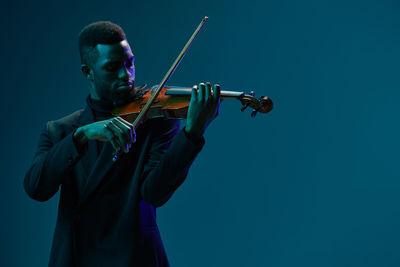 Midsection of man playing violin against clear blue sky