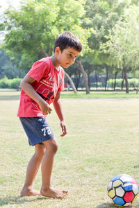 Full length of boy playing soccer on field