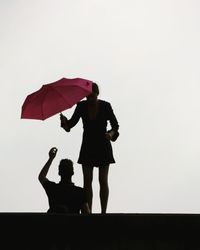 Silhouette of mother with daughter against clear sky