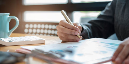 Midsection of man reading book on table