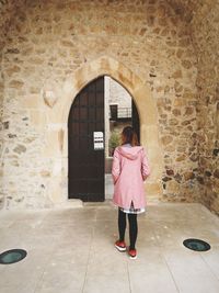 Rear view of woman standing against building