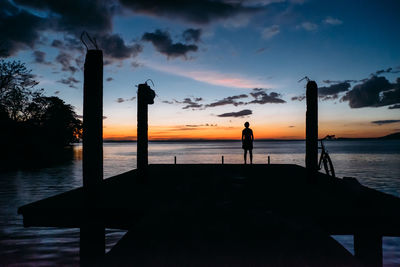 Silhouette people on beach against sky during sunset