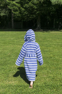 Rear view of boy walking on grassland