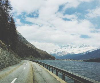 Road by mountains against sky