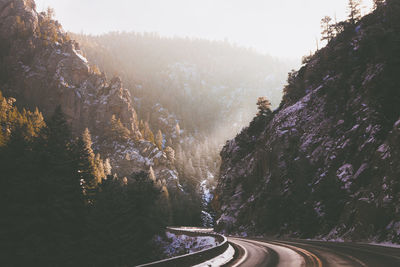 Road amidst trees on mountain in forest against sky