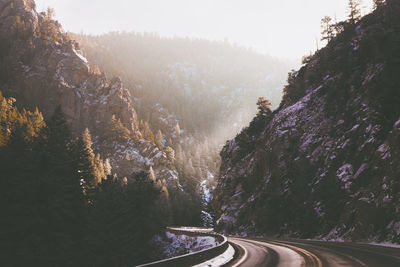 Road amidst trees on mountain in forest against sky