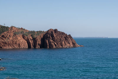 Scenic view of rock formation in sea against clear sky