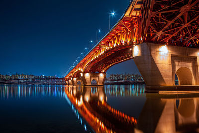 Illuminated bridge over river at night