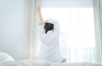 Side view of young woman relaxing on bed at home