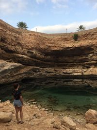 Woman standing on rock against sky