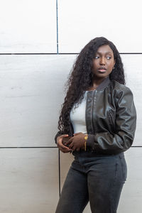 Portrait of young woman standing against wall