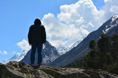 Rear view of man standing on mountain against sky