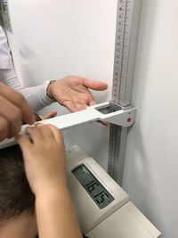 Cropped hands of woman weighing boy