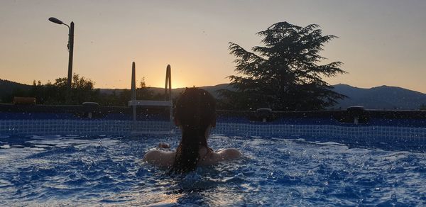 Man standing by swimming pool against sky during winter