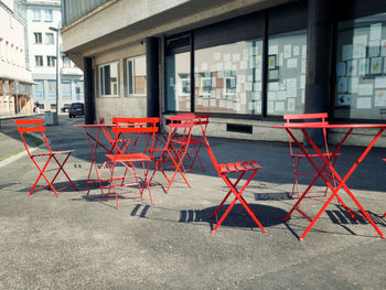 Empty chairs and tables on street in city