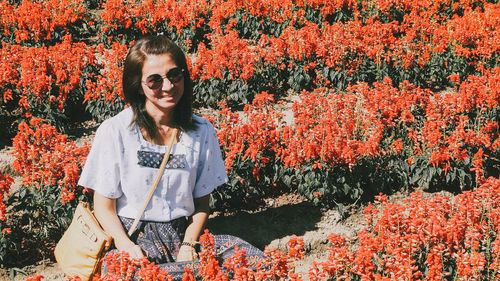 Portrait of woman standing amidst yellow flowering plants on field