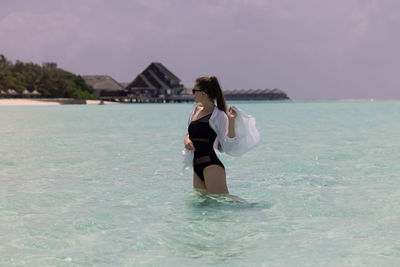 Portrait of young woman in bikini standing in sea