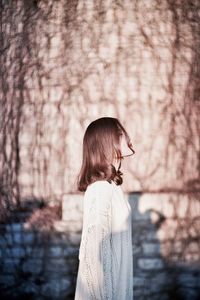 Rear view of woman standing against tree trunk