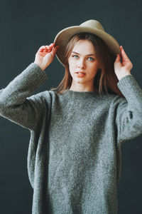Young beautiful long brown-haired hair girl with blue eyes in felt hat and grey knitted sweater
