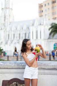 Girl eating mango at the ortiz bridge with la ermita church on background in the city of cali