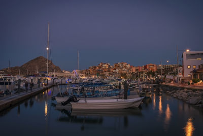 Sailboats moored on river in city at night