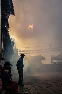 Rear view of people standing against sky during sunset