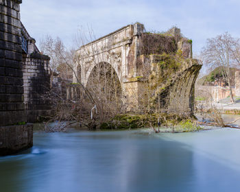 Arch bridge over river against sky