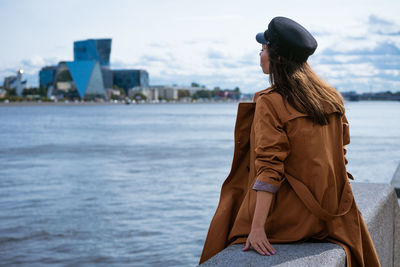 Sad lonely woman sitting on the embankment of the river person