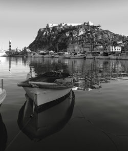 Sailboats moored on harbor by sea against sky