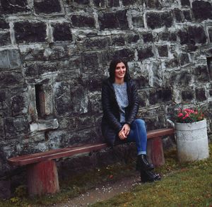 Portrait of woman sitting against wall