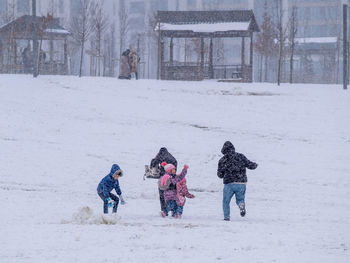 Rear view of kids playing on snow covered land