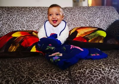 Portrait of cute boy sitting on bed at home